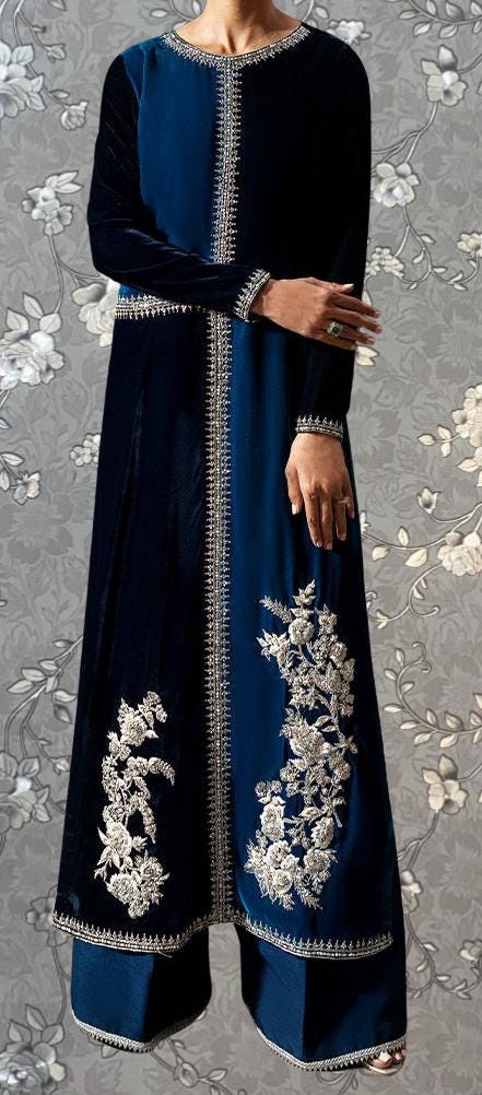 A person wearing a long blue dress with intricate embroidered designs on the sleeves and hem.