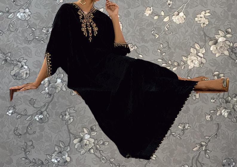 A woman in a black dress with gold accents is sitting on a floating platform against a gray floral background.