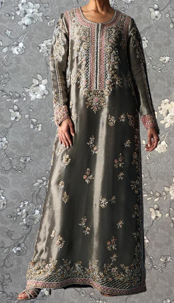 A person wearing a long, gray dress with intricate embroidered patterns and designs.