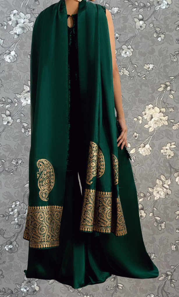 A person wearing a long green dress with gold embroidered patterns on the sleeves and hem.