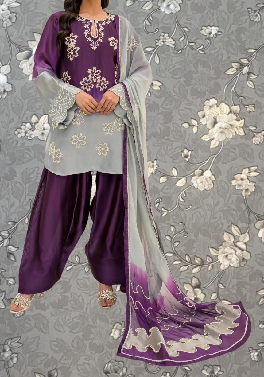 A woman wearing a purple and gray dress with intricate embroidery and a matching shawl stands against a gray floral background.