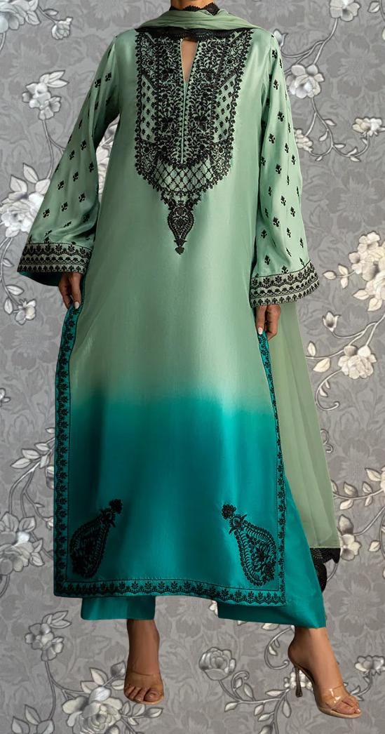 A person wearing a long, green dress with intricate black embroidery and floral patterns.