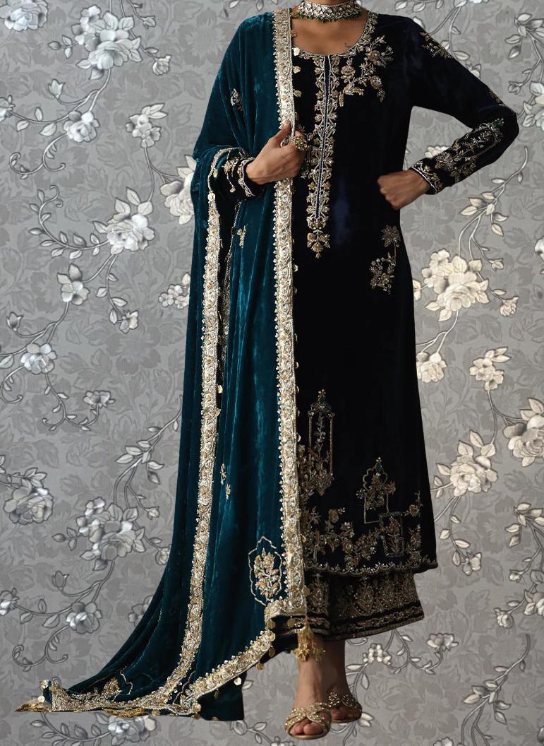 A woman wearing an ornate, long black dress with gold embroidery and a matching green shawl.