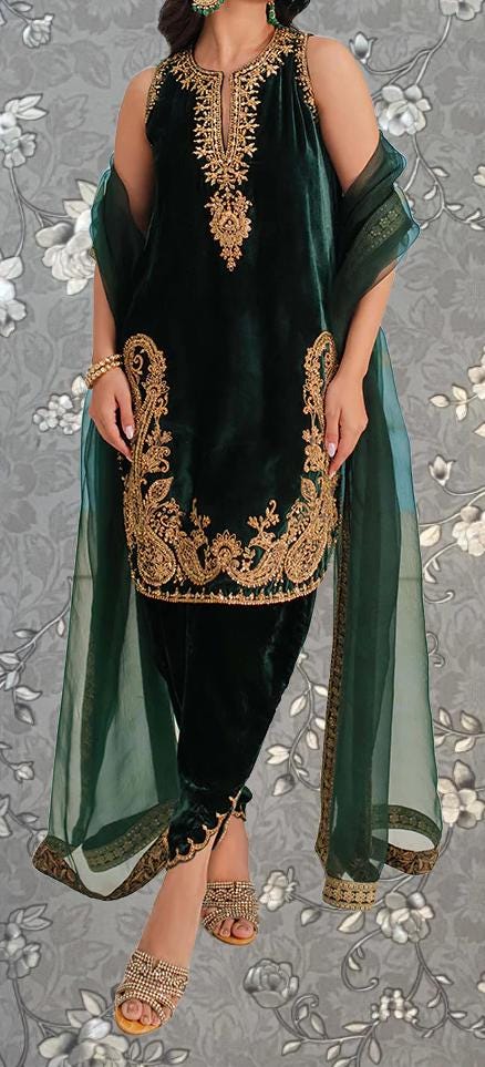 A woman wearing a green velvet dress with gold embroidery and a matching green shawl.