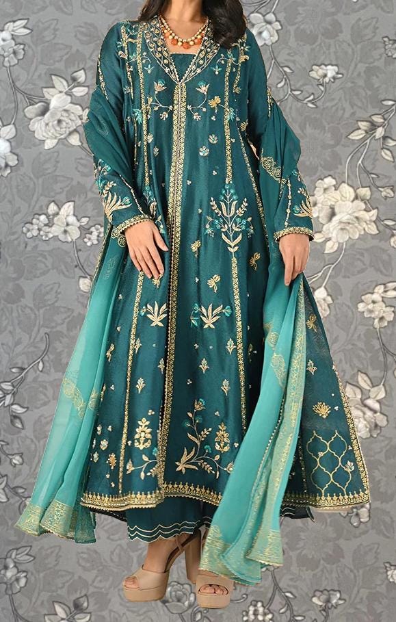 A woman wearing a long, green dress with gold embroidery and a matching green shawl.