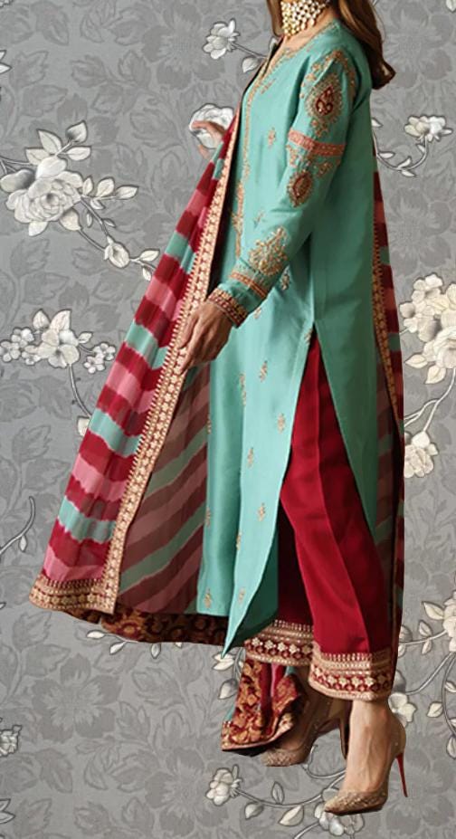 A woman wearing a turquoise and red dress with a red and gold patterned skirt, standing against a gray floral background.