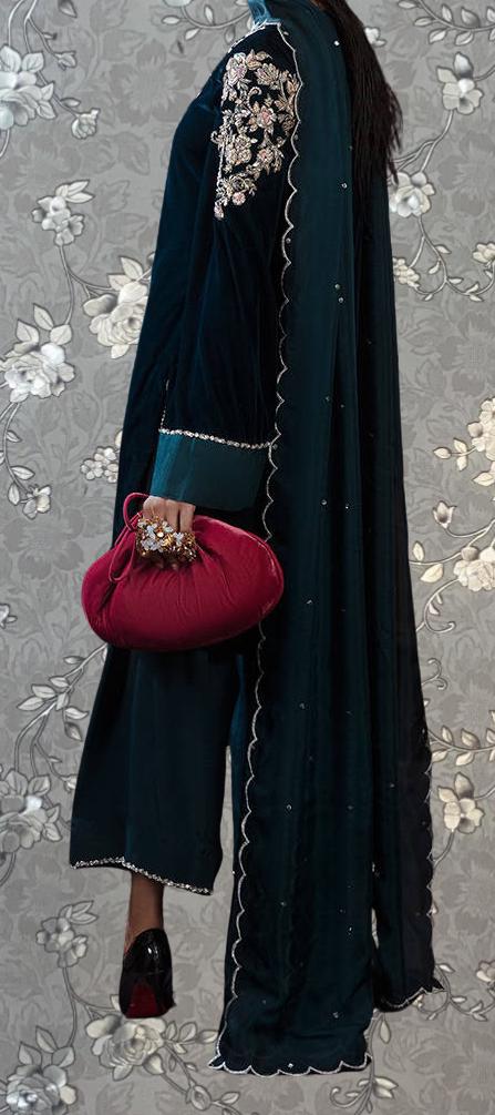 A person wearing a long, dark blue dress with a floral pattern and a matching blue shawl. They are holding a red clutch purse.
