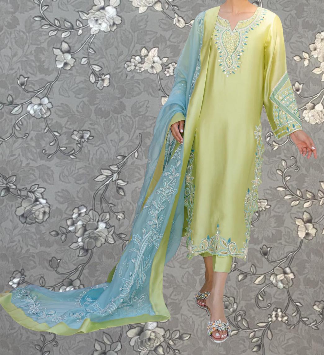 A woman wearing a long, yellow dress with intricate embroidery and a matching blue shawl.
