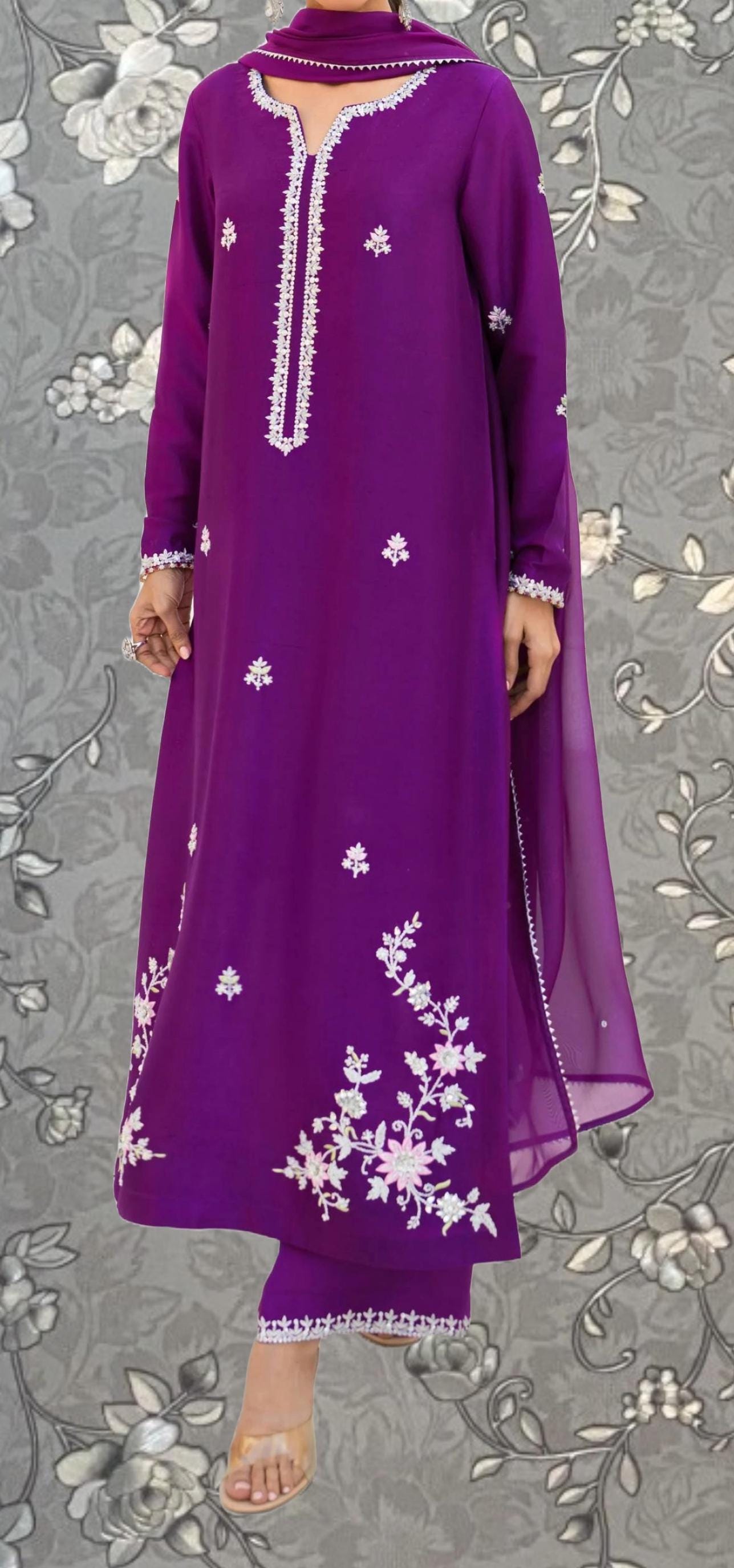 A person wearing a long purple dress with white floral embroidery on the front.
