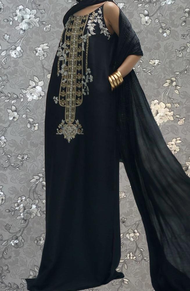 A woman wearing a long black dress with gold embroidery and a flowing black shawl.