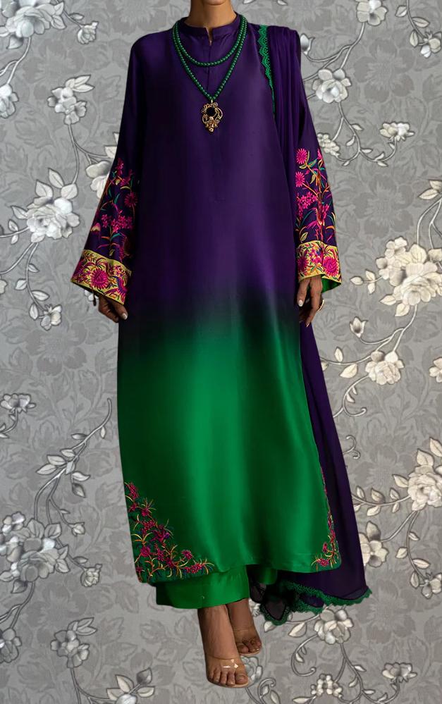 A person wearing a long purple dress with green accents, including embroidered patterns and a matching green scarf.
