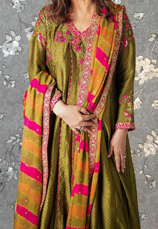 A woman wearing a vibrant green and pink traditional Indian outfit with intricate embroidery and patterns.