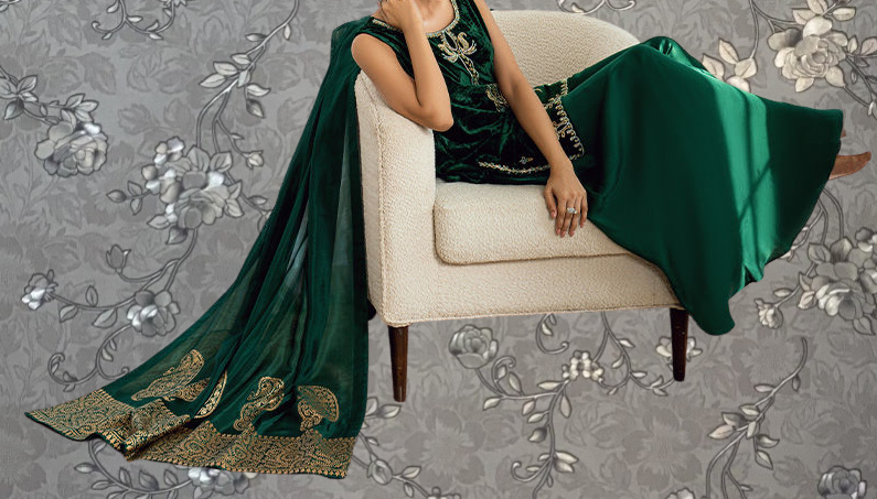 A woman wearing a green and gold dress is sitting on a white chair, with her hand resting on her head.