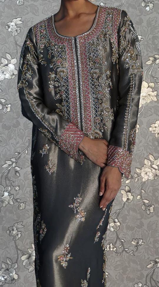 A person wearing a long, gray dress with intricate embroidery and floral patterns.