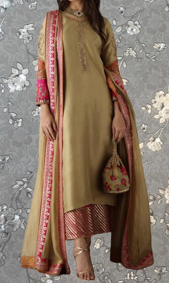 A woman wearing a gold and pink dress with a matching shawl, standing against a gray floral background.