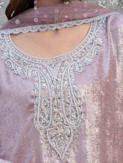 A close-up view of a woman's neck and chest area wearing a pink dress with intricate embroidered patterns and a matching pink scarf.