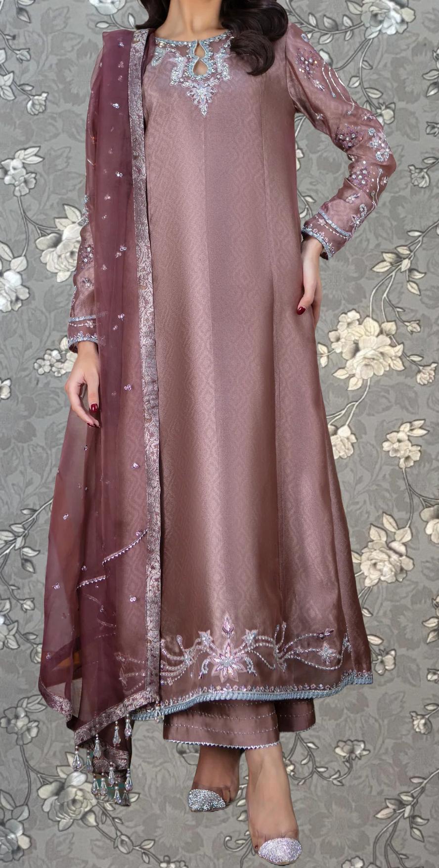 A woman wearing a long, pink dress with intricate embroidery and a matching shawl.