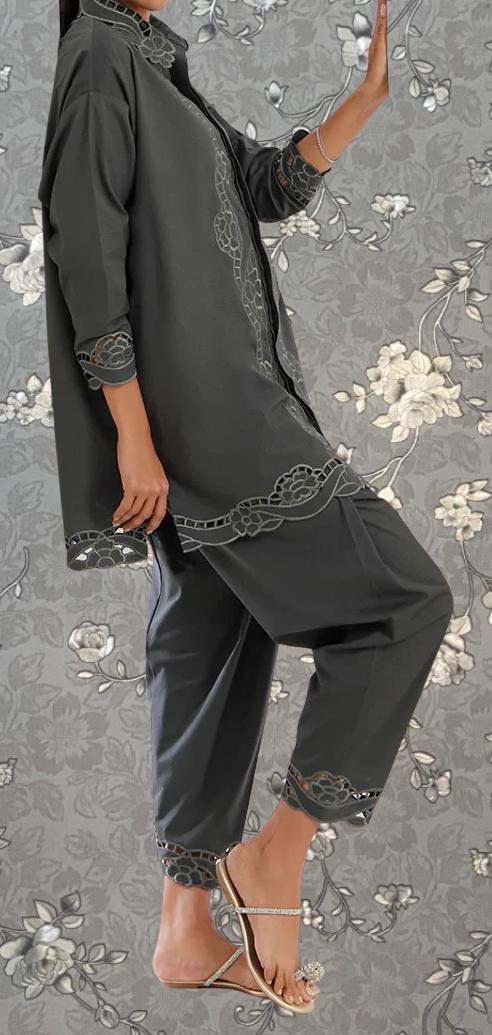 A person wearing a gray outfit with floral embroidery poses against a gray floral background.