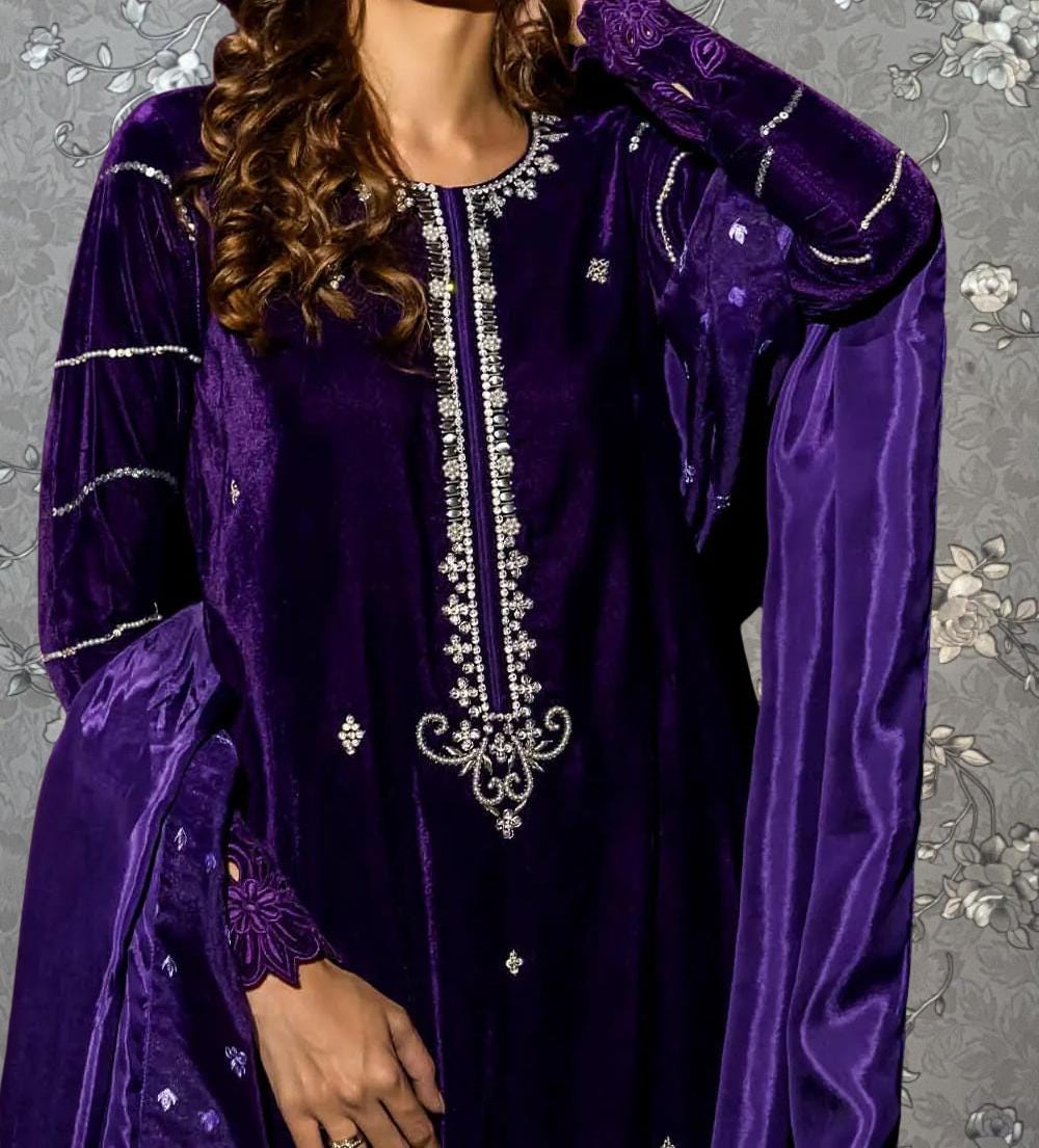 A woman wearing a purple velvet dress with intricate embroidery and a matching purple shawl.