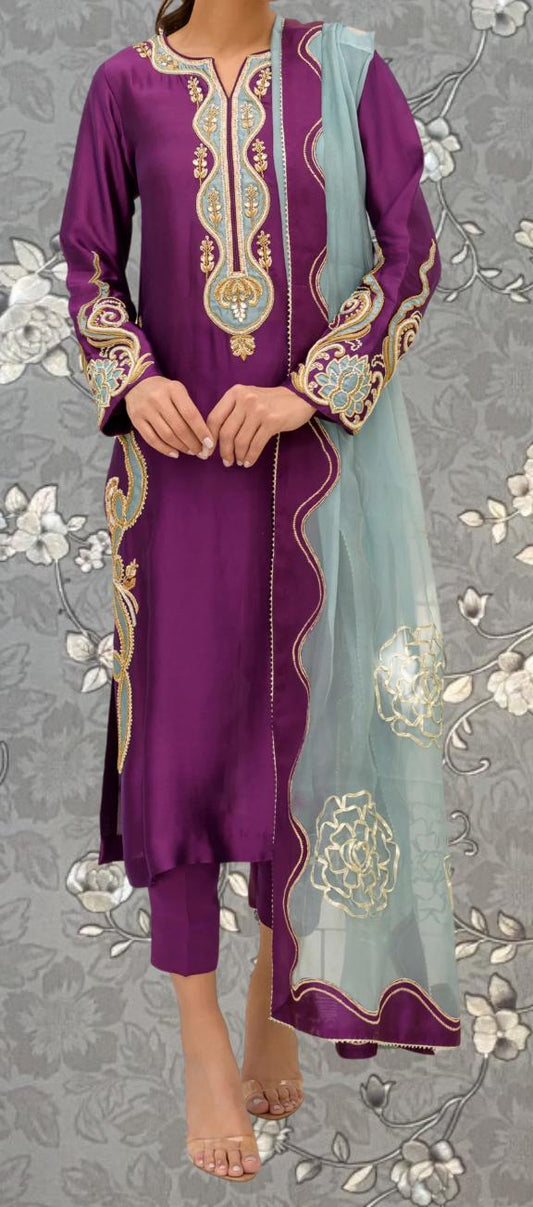 A woman wearing a purple and green dress with intricate embroidery and a matching shawl.