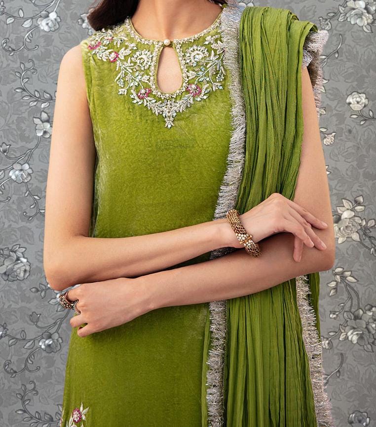 A woman wearing a green dress with a floral pattern and a matching green shawl draped over her shoulders.