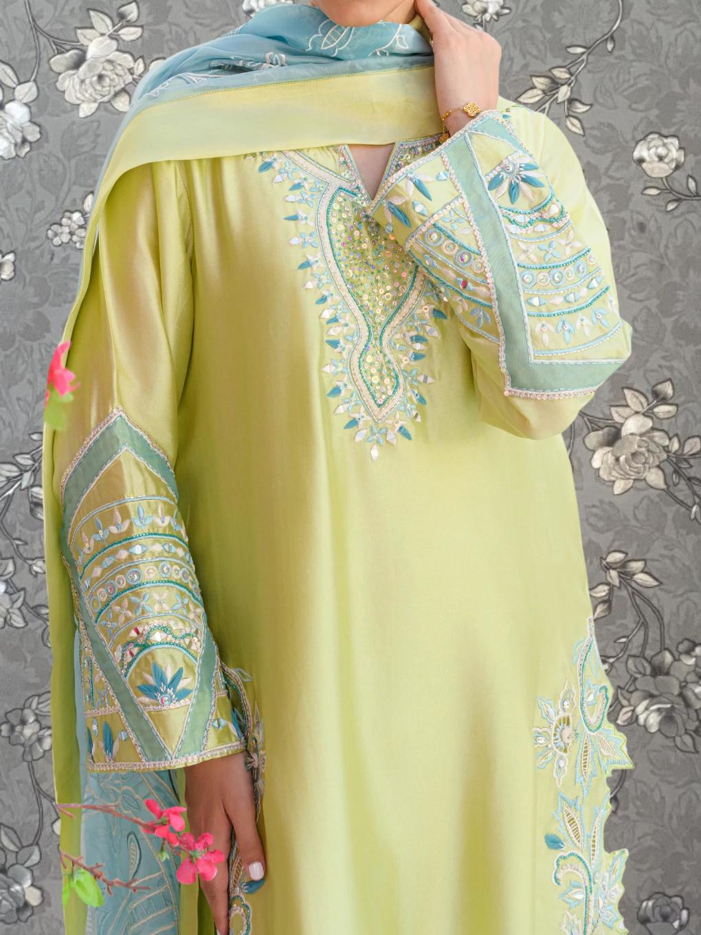 A person wearing a yellow dress with intricate embroidered patterns and a matching scarf.