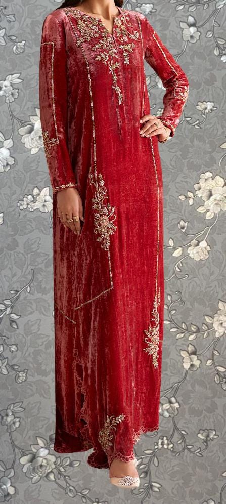 A woman wearing a long, red velvet dress with intricate embroidery and floral patterns.