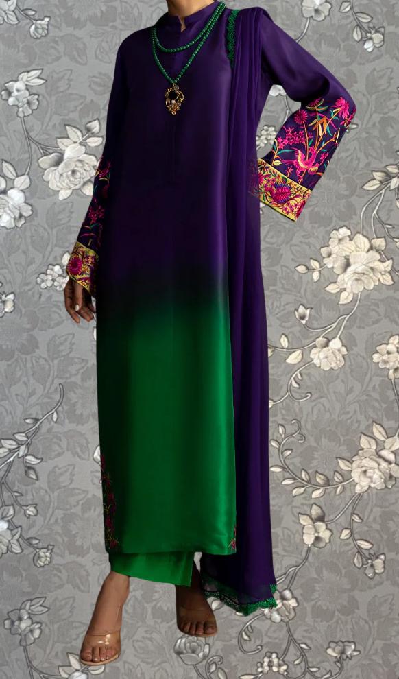 A person wearing a long purple dress with green accents, standing against a gray floral background.