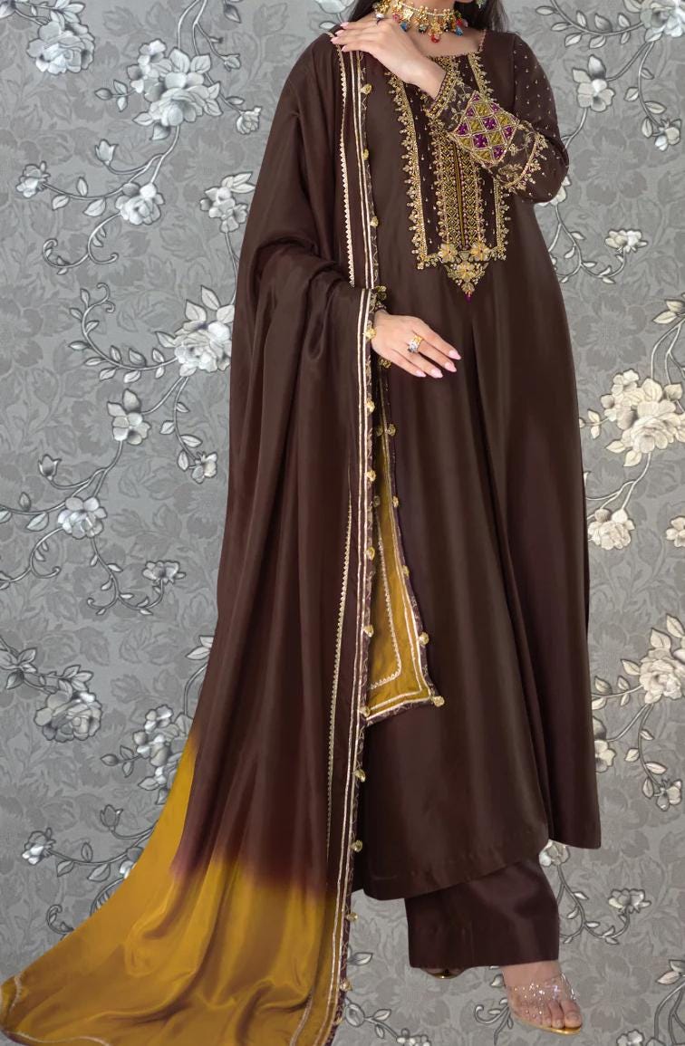A woman wearing a brown and gold dress with a long, flowing skirt and a matching shawl.