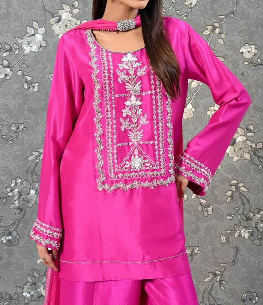 A woman wearing a bright pink dress with intricate embroidered designs on the front.