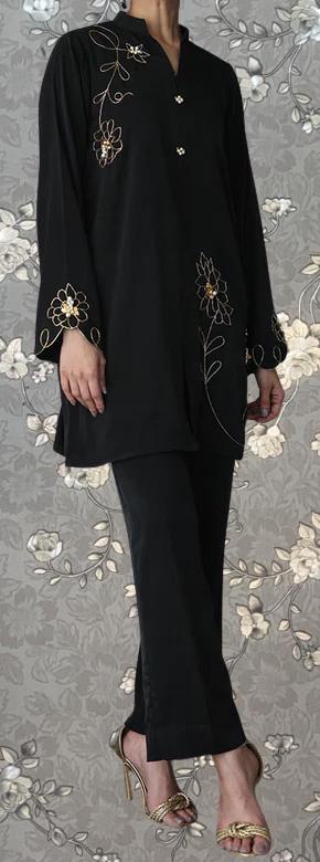 A person wearing a black outfit with gold floral embroidery stands against a floral background.
